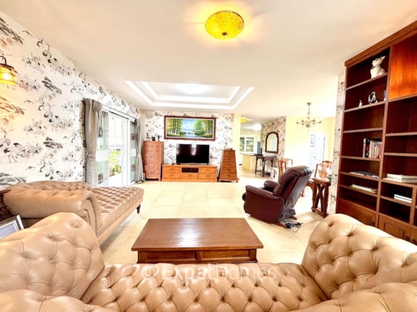 Open-plan living room with tufted beige leather sofas, a wooden coffee table, and a TV on a wooden console.