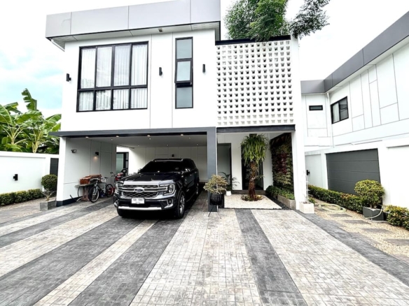 Modern white two-story house with a covered carport and a black SUV parked on a striped driveway.