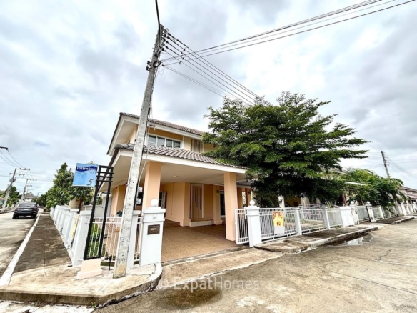 Two-story peach house with a tiled roof, gated front yard, and a large tree, on a corner lot along a quiet street.
