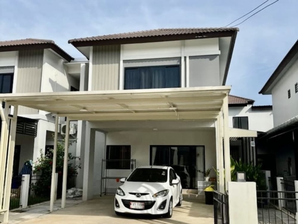 White sedan parked under a covered driveway in front of a modern two-story house with beige and gray exterior.