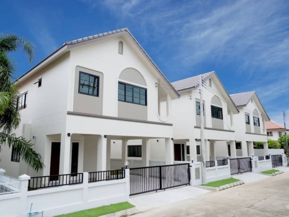 Row of white two-story townhouses with gated entrances under a blue sky.