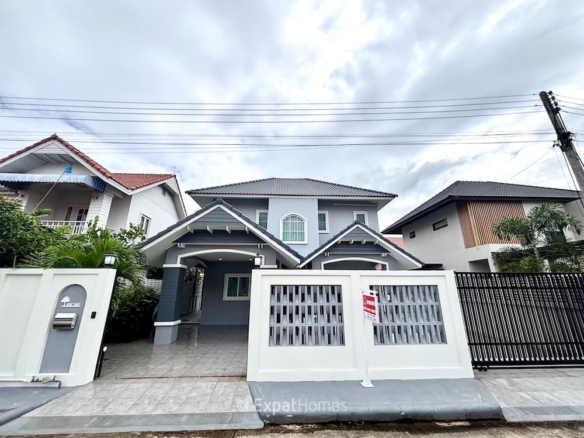 Modern two-story gray house with white trim, gated driveway, and small front yard.