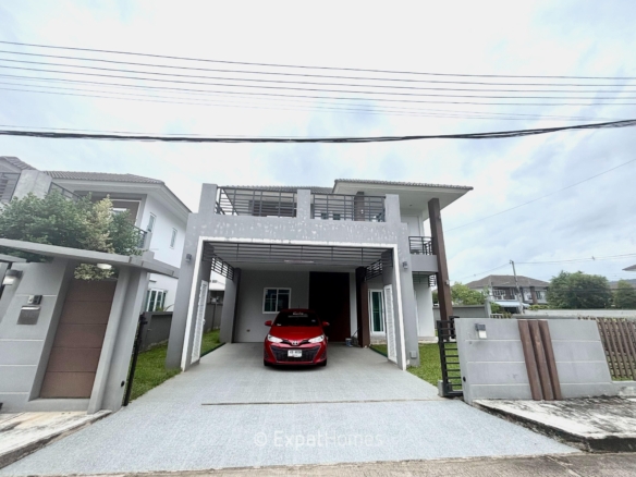 Two-story modern house with a covered carport; a red car parked in the driveway.