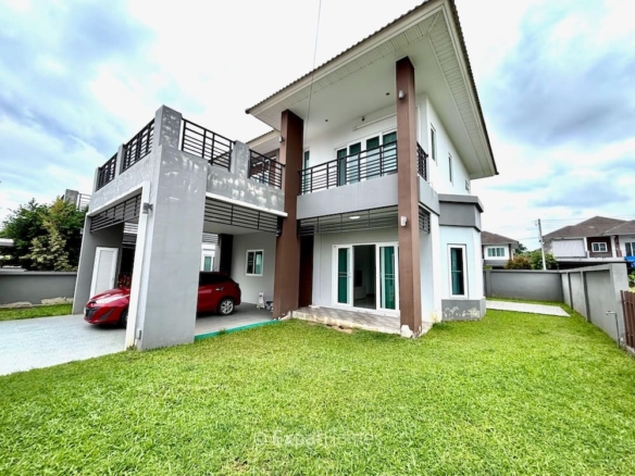 Modern two-story house with gray and white exterior, brown columns, and a red car in the carport on a green lawn.