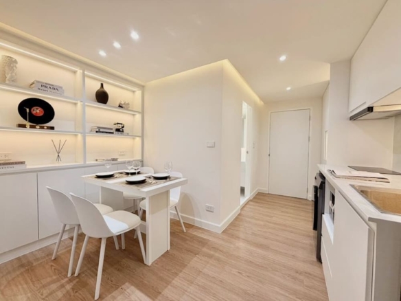 Bright white, minimalist kitchen with open shelves and a small four-seat dining table on a light wooden floor.