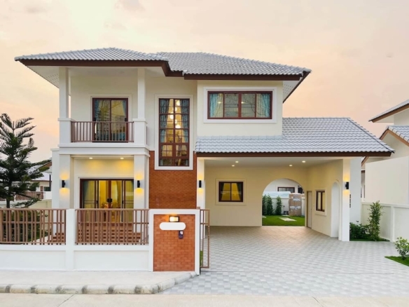 Two-story modern house with brick and white exterior, gated front yard, and tiled roof.