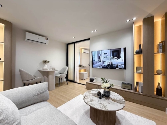 Modern living room with a gray sofa, round marble coffee table, and a wall-mounted TV with illuminated shelving.